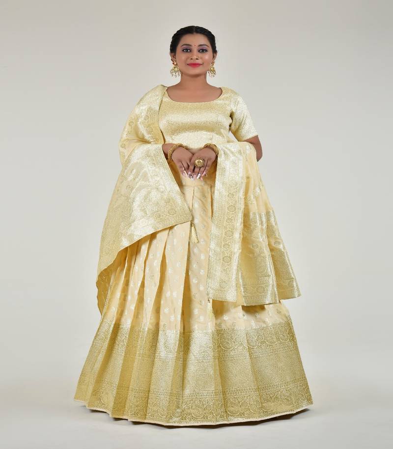 Regal Banarasi Cream  Lehenga Choli Set With Opulent Gold Zari Work, Unstitched Blouse And Matching Banarasi Dupatta.