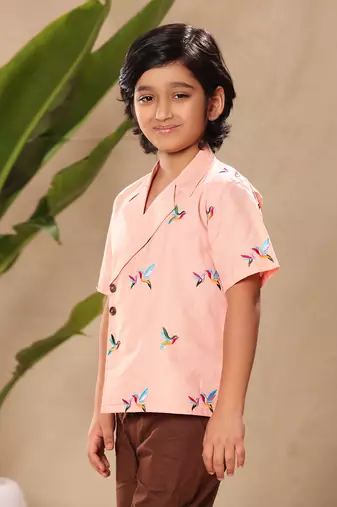 Pink embroidered blazer style shirt with brown trousers