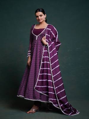A regal deep purple anarkali dress adorned with a bandhani-inspired pattern and detailed piping along the edges. 2