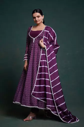 A regal deep purple anarkali dress adorned with a bandhani-inspired pattern and detailed piping along the edges.
