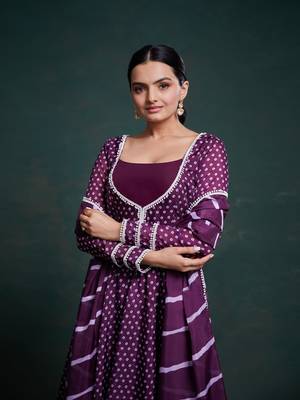 A regal deep purple anarkali dress adorned with a bandhani-inspired pattern and detailed piping along the edges. 3