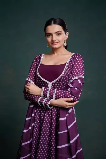 A regal deep purple anarkali dress adorned with a bandhani-inspired pattern and detailed piping along the edges.