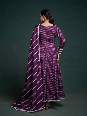 A regal deep purple anarkali dress adorned with a bandhani-inspired pattern and detailed piping along the edges. 4