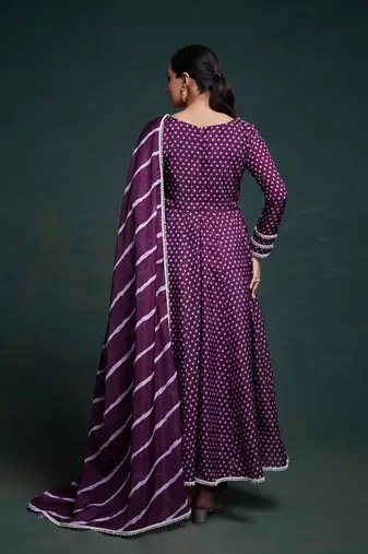A regal deep purple anarkali dress adorned with a bandhani-inspired pattern and detailed piping along the edges.