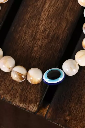 Nvr unisex cream-colored evil eye elasticated rakhi with roli chawal
