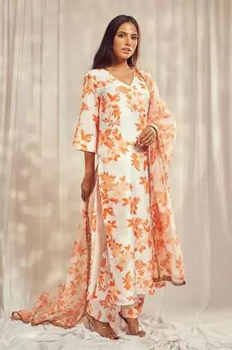Burnt orange print kurti set paired with matching bottom and star organdie dupatta with gold trimming lace detailing.