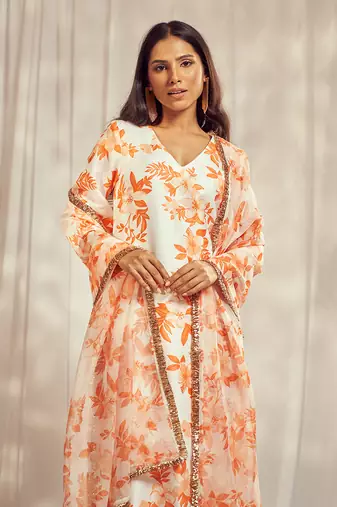 Burnt orange print kurti set paired with matching bottom and star organdie dupatta with gold trimming lace detailing.