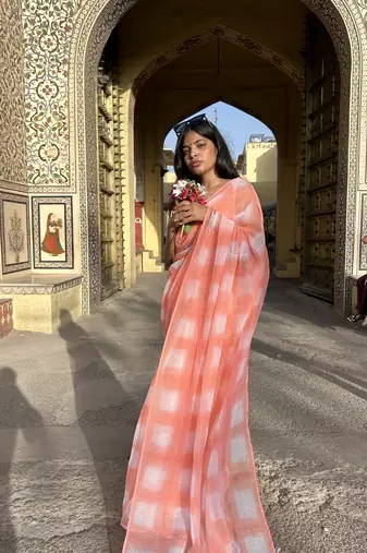 Grace and tradition meet in the exquisite Kota Doria Peach Saree.