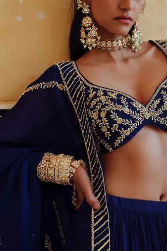 DEEP NECKLINE EMBROIDERED SLEEVELESS BLOUSE WITH FLORAL BUTTI EMBROIDERED LEHENGA AND DUPATTA