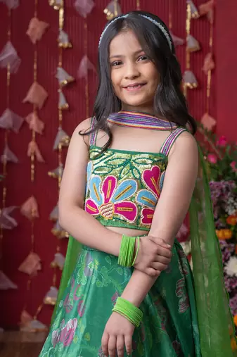 Grace your festivities with this vibrant green lehenga set, featuring floral embroidery and a flowy printed skirt
