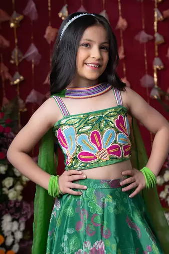 Grace your festivities with this vibrant green lehenga set, featuring floral embroidery and a flowy printed skirt