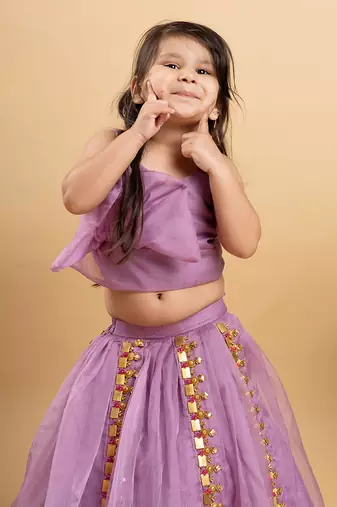 Chic lavender lehenga with an asymmetrical top, adorned with gold and pink embellishments for a modern festive look.