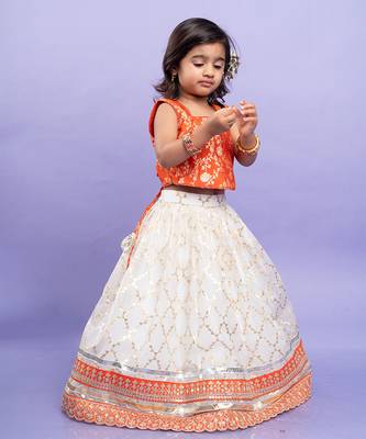 Festive orange brocade top with a golden-patterned white lehenga, perfect for celebrations 1