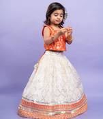 Festive orange brocade top with a golden-patterned white lehenga, perfect for celebrations