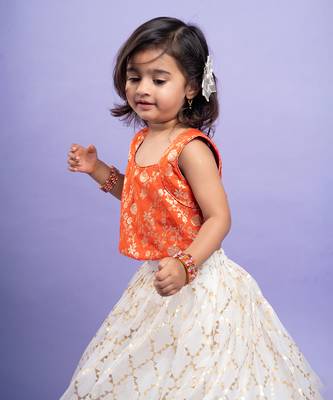 Festive orange brocade top with a golden-patterned white lehenga, perfect for celebrations 2
