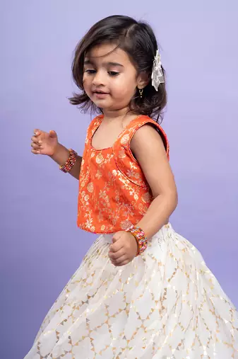 Festive orange brocade top with a golden-patterned white lehenga, perfect for celebrations