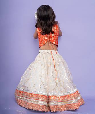 Festive orange brocade top with a golden-patterned white lehenga, perfect for celebrations 3