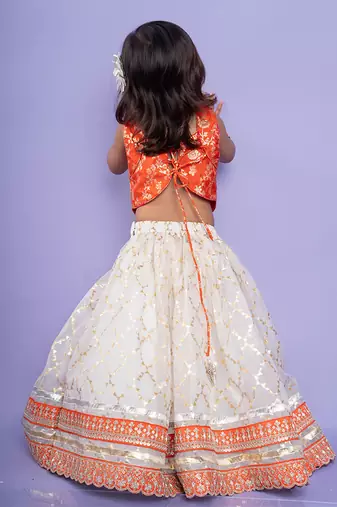 Festive orange brocade top with a golden-patterned white lehenga, perfect for celebrations