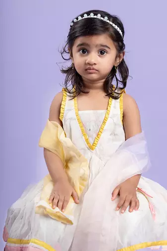 Charming white dhoti-style set with floral embroidery and playful yellow and pink accents, perfect for festive occasions