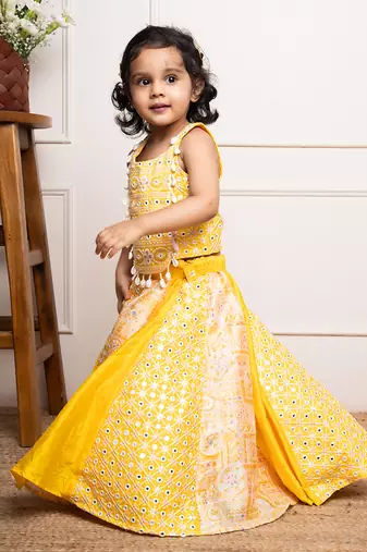 Vibrant yellow sleeveless dress with playful prints and tassel accents.