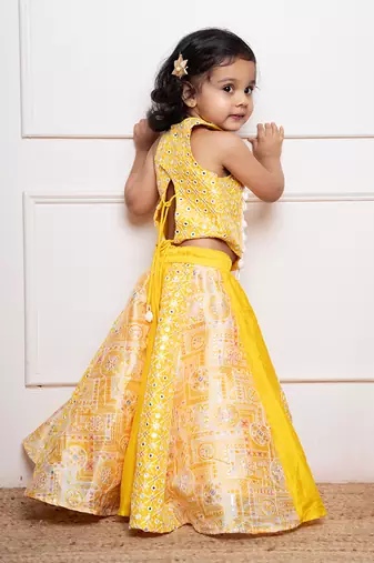 Vibrant yellow sleeveless dress with playful prints and tassel accents.