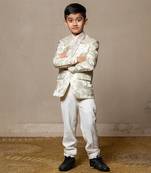 Elegant brocade suit jacket with floral patterns paired with crisp white trousers and a classic ivory shirt