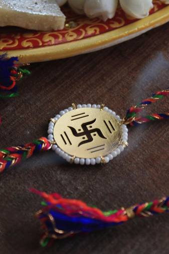 Golden beaded swastik rakhi with roli chawal