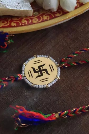 Golden beaded swastik rakhi with roli chawal