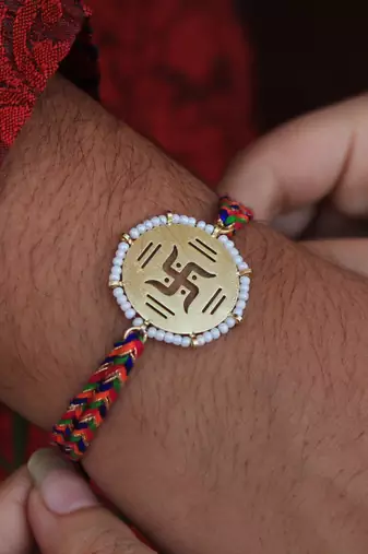 Golden beaded swastik rakhi with roli chawal