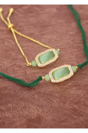 Mint green stone and crystal-studded unisex rakhi set for bhaiya bhabhi with roli chawal and written greeting note.