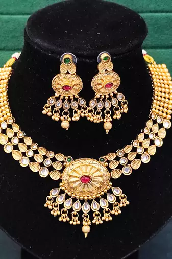 Beautiful gold-plated kundan necklace and earrings set with red and green stones, pearl accents for her