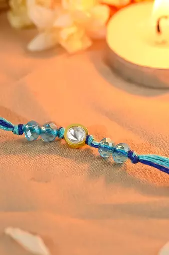 Blue thread rakhi with gold-framed stone and crystal beads