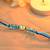 Blue thread rakhi with gold-framed stone and crystal beads