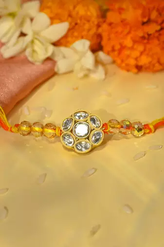 Yellow thread rakhi with floral stone motif and crystal beads