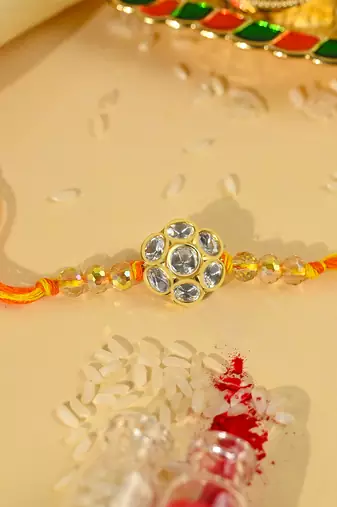 Yellow thread rakhi with floral stone motif and crystal beads