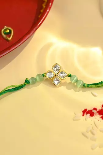 Green thread floral rakhi with four-stone motif and beads