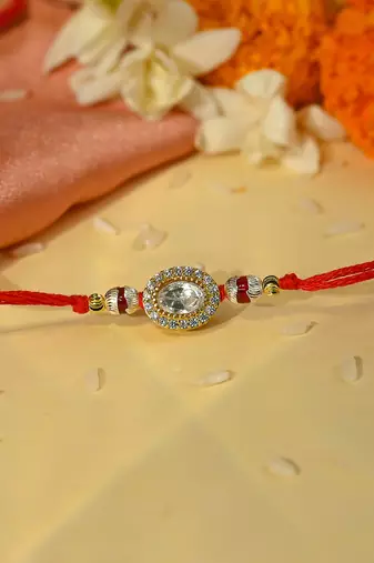 Red thread rakhi with oval stone halo and minimal bead accents