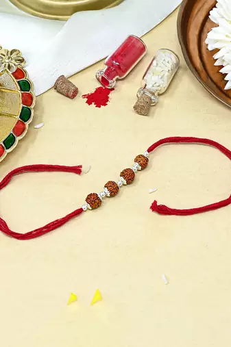 Red thread rakhi with four rudraksha beads and silver detailing