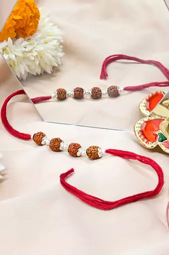 Red thread rakhi with four rudraksha beads and silver detailing