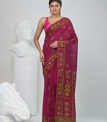 Magenta cotton saree with traditional woven patterns and tassel border