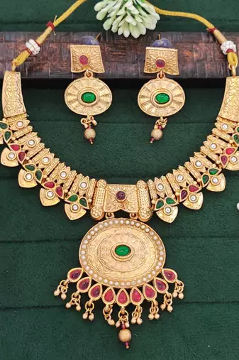 temple necklace set with green and ruby stones, intricate detailing and matching earrings