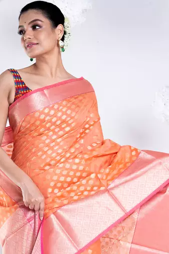Banarasi kora organza saree in sunset orange color with golden border and booti