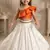Orange one-shoulder top with ivory skirt