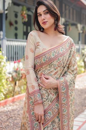 Ivory handloom cotton-linen saree with floral and peacock motifs, zari highlights, and tassel finish