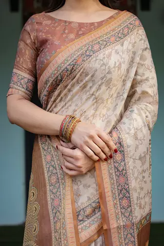 Ivory handloom cotton-linen saree with floral and peacock motifs, zari highlights, and tassel finish