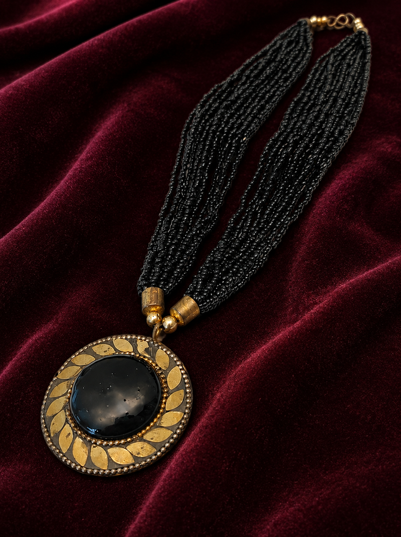 Black multi-strand beaded necklace with round gold leaf pendant, ethnic statement jewellery