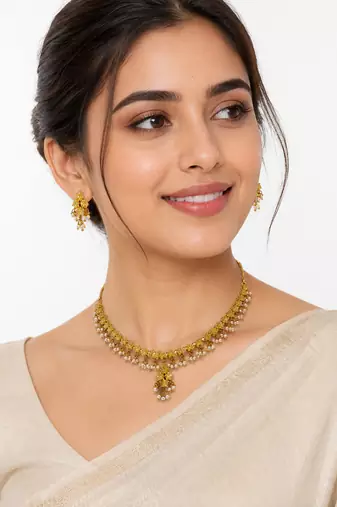 Gold-toned floral necklace and earrings set with pearl drops, traditional indian jewellery