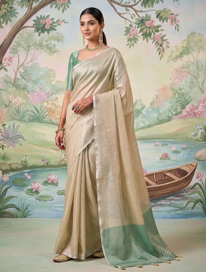 Beige colour tissue silk saree with silver grey pallu & tassels