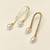 Gold-tone hammered arc drop earrings with freshwater pearl dangles, elegant stud style