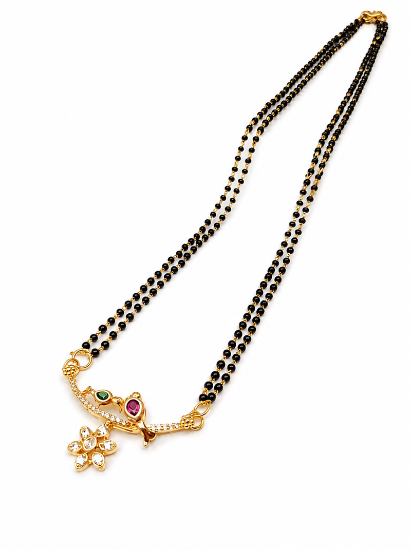 Traditional double strand black bead mangalsutra with gold-toned floral cz pendant, ruby & emerald accents
